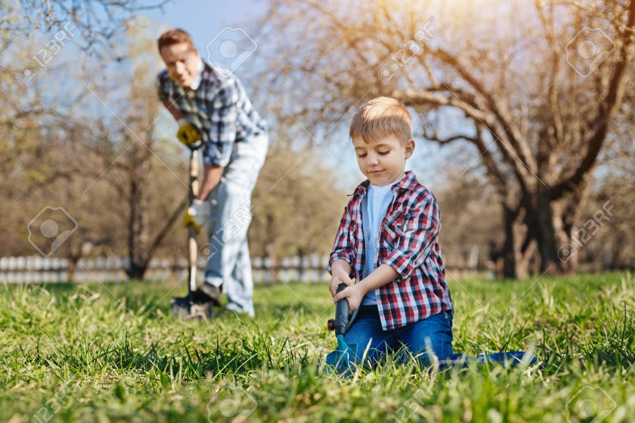 Little boy helping his father in garden